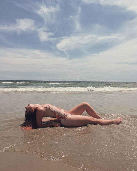picture of me laying on a beach in the shallow water